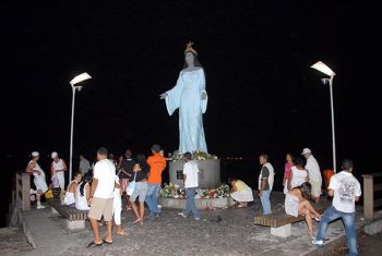 devotos levando flores para estátua de Iemanjá na praia de Camburi