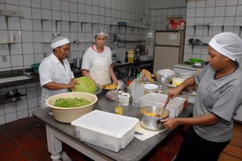 Auxiliar de cozinha e cozinheiras preparando almoço