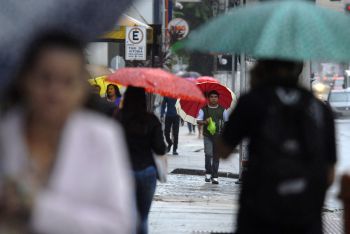 Transeuntes na Avenida Nossa Senhora da Penha em dia de chuva