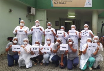 Equipe de saúde da unidade de São Pedro segura cartazes onde pede para a população ficar em casa